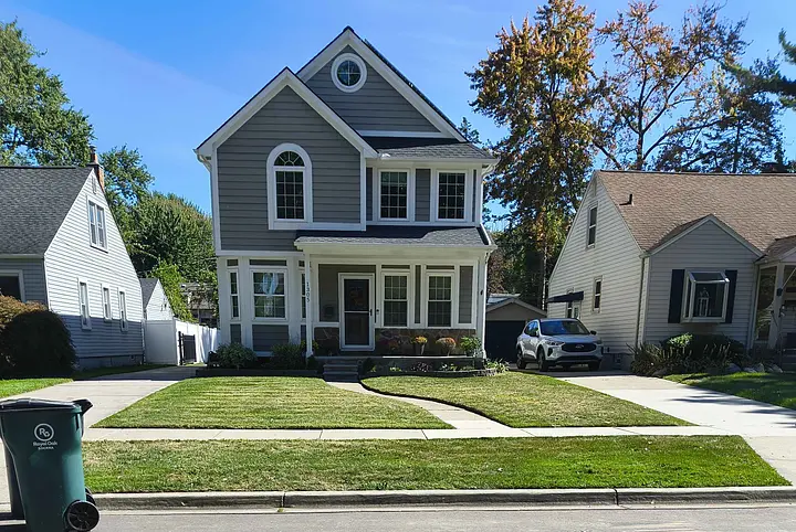 A two-story gray house with white trim and a manicured lawn.